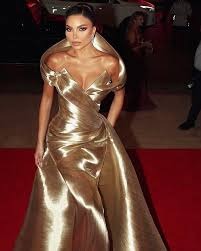 Gold metallic off-shoulder evening gown with sculptural draping.